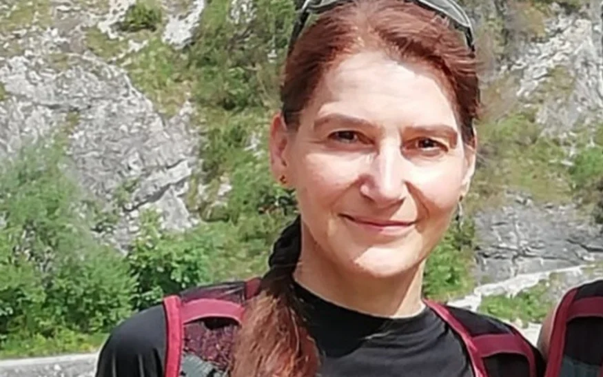 Frau mit rotem Rucksack und schwarzem T-Shirt vor Berglandschaft