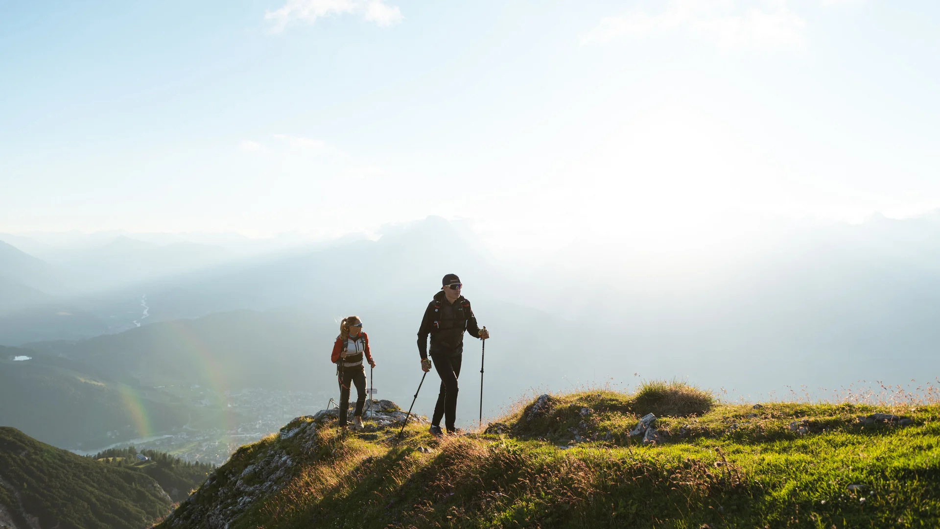 Urlaub in Bewegung: Ihr Aktivhotel in Tirol Zwei Wanderer auf einem grasbewachsenen Berg bei Sonnenlicht