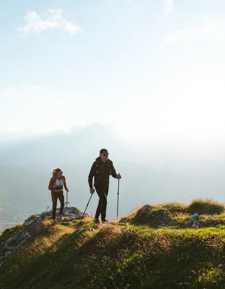 Zwei Wanderer auf einem grasbewachsenen Berg bei Sonnenlicht