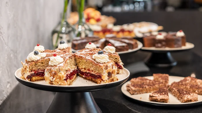 Das Hotel mit Bio-Küche in Tirol Verschiedene Kuchenstücke auf schwarzen und weißen Tortenständern auf einem Tisch