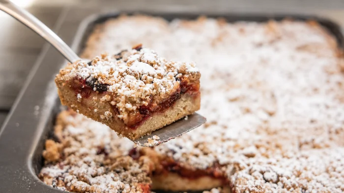 Das Hotel mit Bio-Küche in Tirol Ein Stück Streuselkuchen mit Puderzucker auf einem Kuchenheber