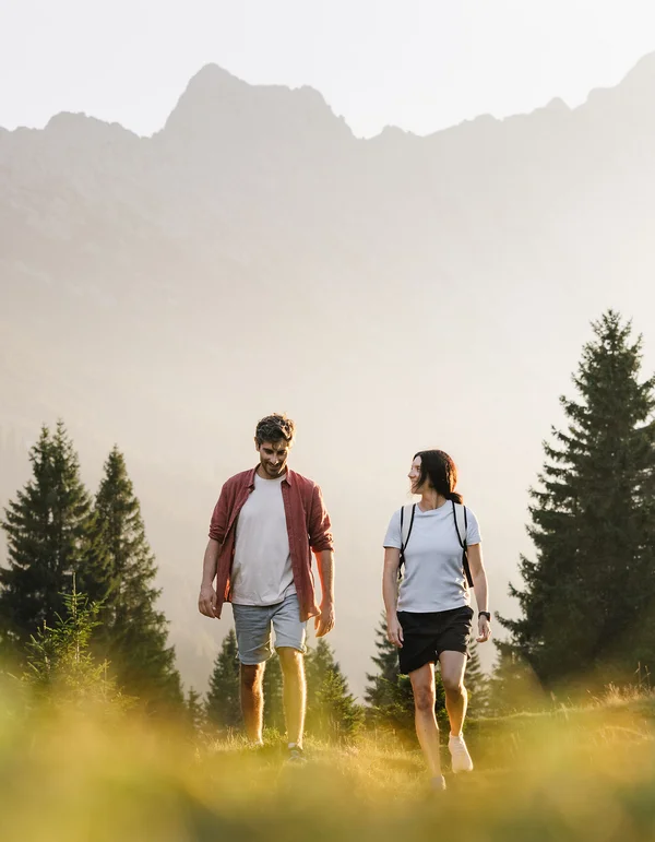 Your sport hotel in Austria: Leutascherhof Couple walking on a forest trail with mountains in the background