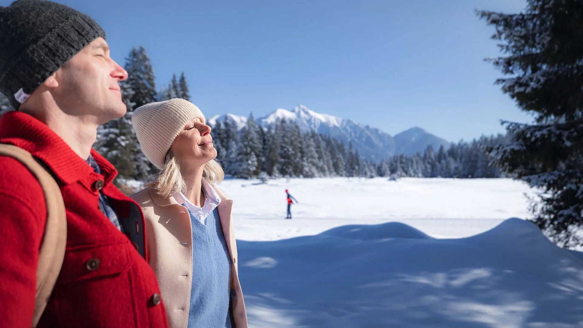 Paar genießt die Wintersonne in verschneiter Berglandschaft