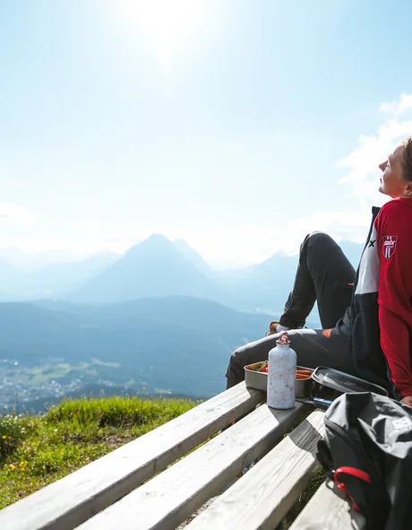 Der Bio-Blog des Leutascherhof Frau sitzt auf Bank mit Bergblick bei sonnigem Wetter