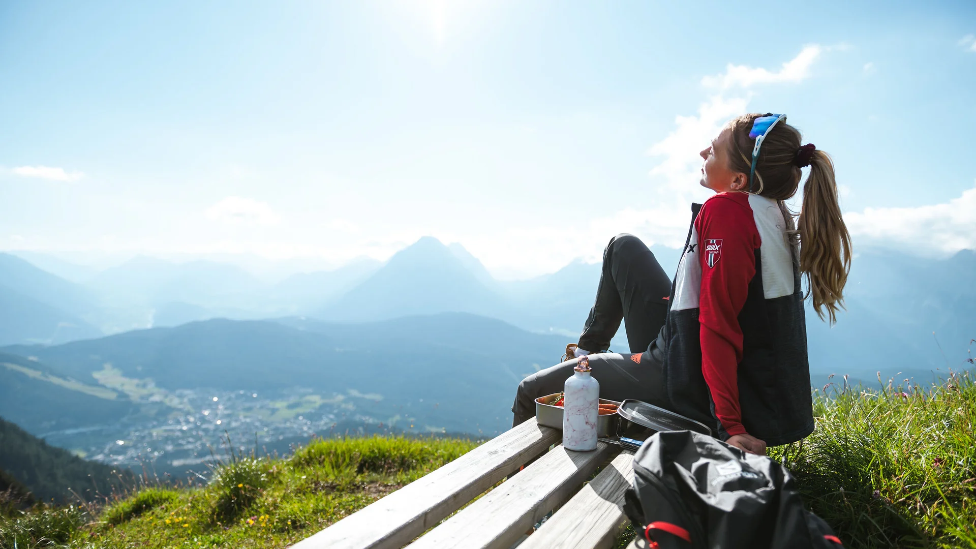 Urlaub in Bewegung: Ihr Aktivhotel in Tirol Frau sitzt auf Bank mit Bergblick bei sonnigem Wetter