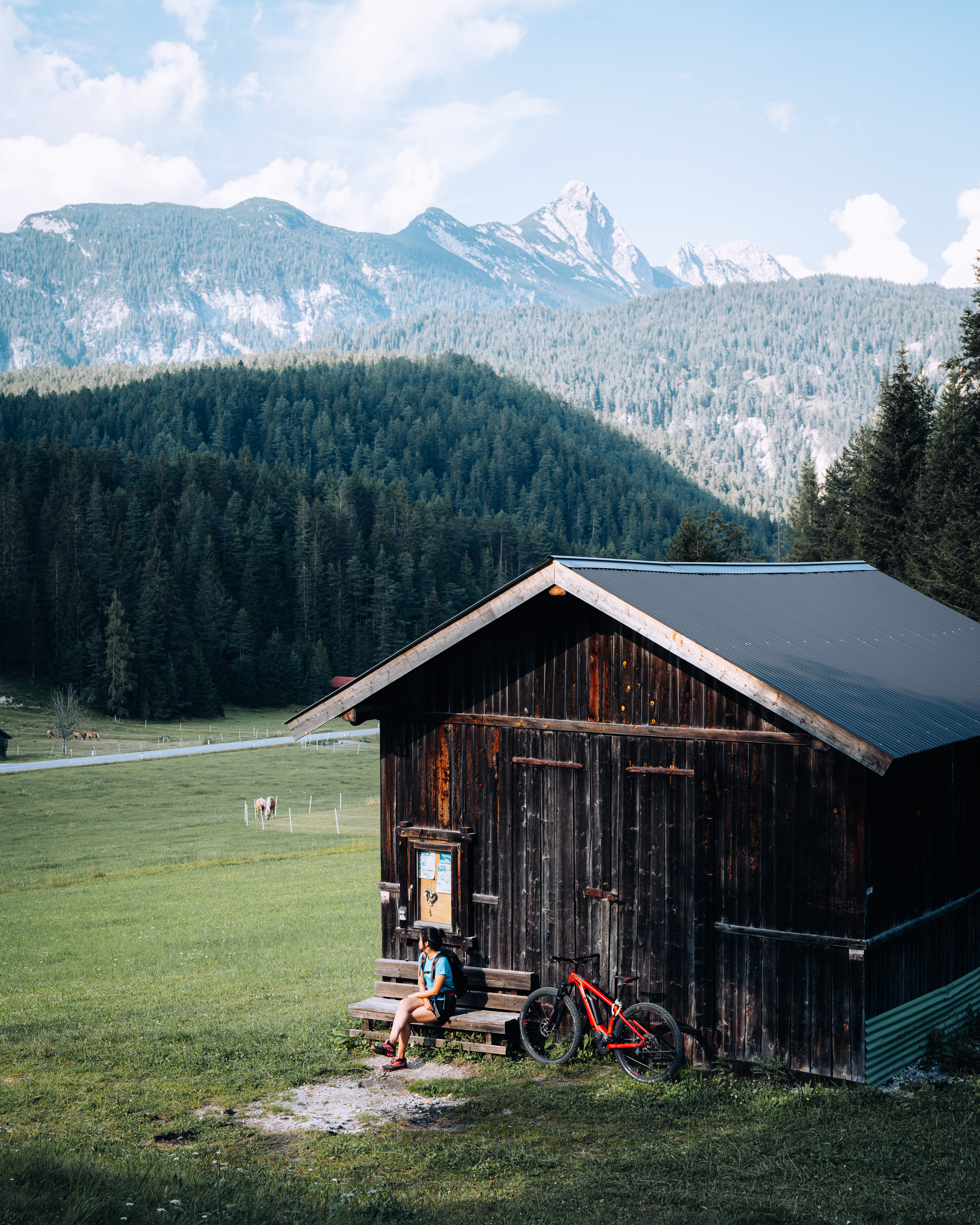 Werfen Sie einen Blick in die Bildergalerie Person sitzt neben Hütte mit Rad in Berglandschaft